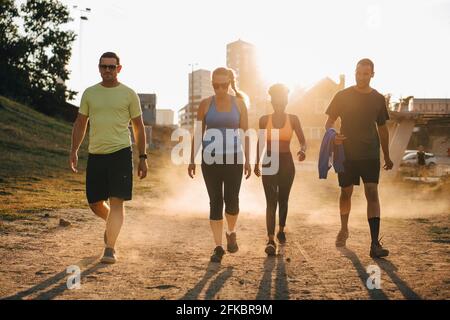 Male and female athletes walking on land during sunny day Stock Photo