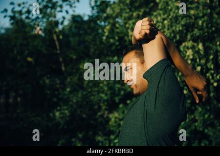 Sportsman doing stretching exercise in park Stock Photo