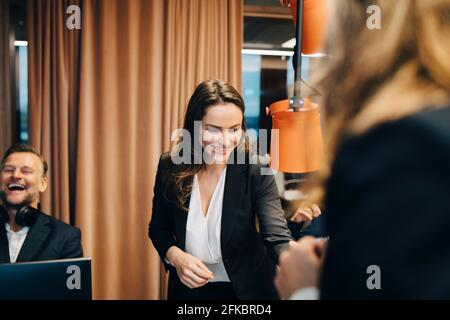 Happy male and female colleagues discussing during meeting at office Stock Photo