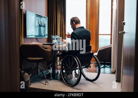 Disabled businessman with colleagues on video conference in office during pandemic Stock Photo