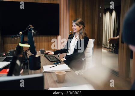 Happy female entrepreneur working on computer in office Stock Photo