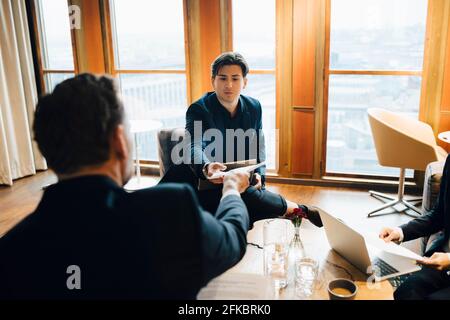 Male colleagues discussing over document in office Stock Photo