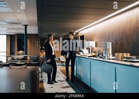 Male and female colleagues discussing in office cafeteria Stock Photo