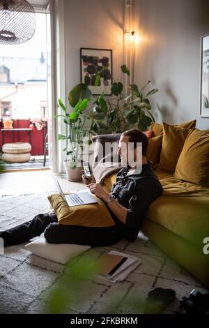 Businessman using smart phone while working at home during pandemic Stock Photo