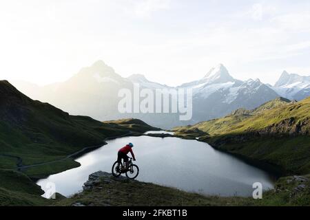 Mountain biker riding downhill at Bachalpsee lake at dawn, Grindelwald, Bernese Oberland, Bern Canton, Switzerland, Europe Stock Photo