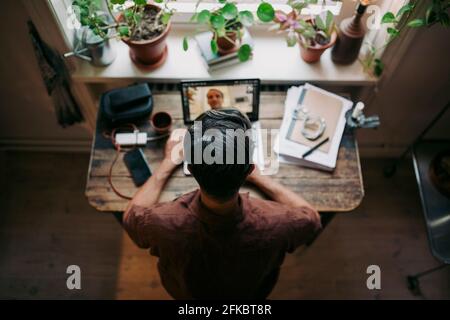 Directly above shot of businessman on video call through laptop with male colleague at home office Stock Photo