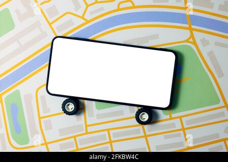 carsharing, car rental and taxi service mobile app - phone with wheels and blank screen on city map Stock Photo