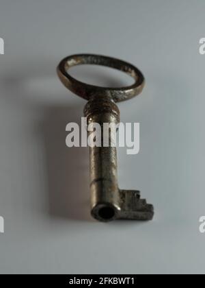 A golden key isolated on white background. Old rusty door key. Antique gold key. DOF. Stock Photo