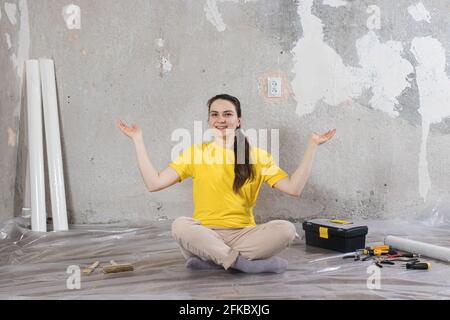 A female builder is doing repairs in the house. Repairing the key, putty and wallpaper Stock Photo