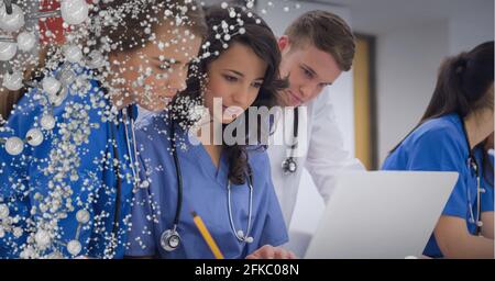 Composition of white molecules over male and female doctors using laptop Stock Photo