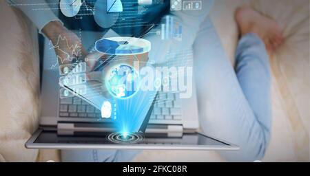 Composition of screen with data processing over woman sitting on sofa using laptop Stock Photo