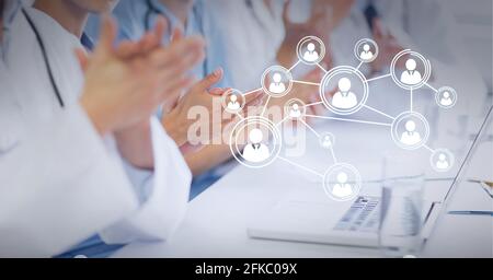 Connected network of bubbles with people icons over medical workers sitting at table Stock Photo