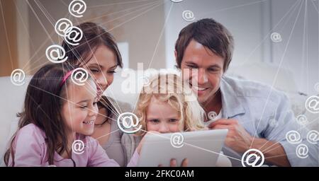 Composition of network of connections with email icons over family using tablet at home Stock Photo