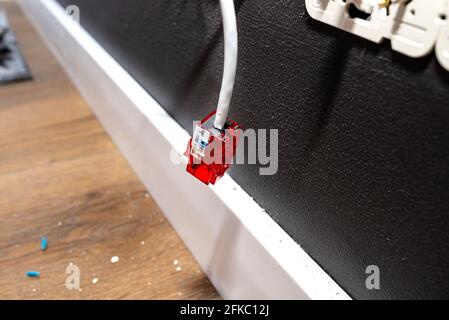 A network cable protruding from the wall with a ready RJ45 module to the computer socket in the room. Stock Photo