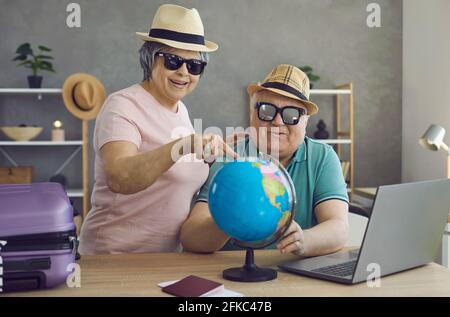 Happy retired couple planning holiday trip and choosing their dream destination on globe Stock Photo
