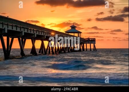 The sun peeks through the railings of the Deerfield Beach International Fishing Pier at sunrise Stock Photo