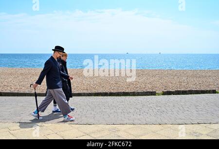 Brighton, UK. 30th Apr, 2021. A dapper young man enjoys a stroll along Brighton seafront on a beautiful sunny day but the weather is forecast to turn wet and windy over the weekend though especially on Bank Holiday Monday : Credit: Simon Dack/Alamy Live News Stock Photo