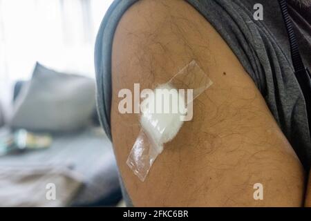 Brown male arm with a bandage after receiving the covid-19 vaccine. Body part. Vaccination against covid pandemic  Stock Photo