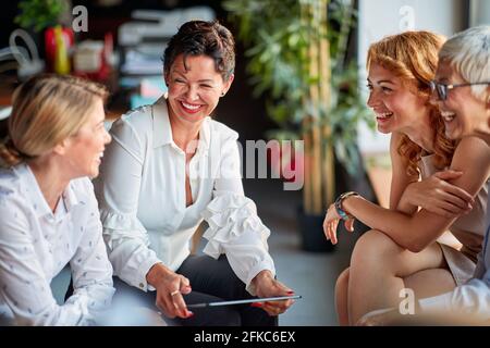 Group of cheerful business women have a good time while talking during a break in a friendly atmosphere at workplace. Business, office, job Stock Photo