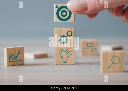 Business strategy, action plan, management concept. Businesswoman hand putting wood cube block with target icon on top of other cubes with business Stock Photo