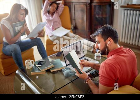 Group of three students writing paper together at home Stock Photo