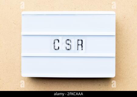 White lightbox with word CSR (Abbreviation of corporate social responsibility) on wood background Stock Photo