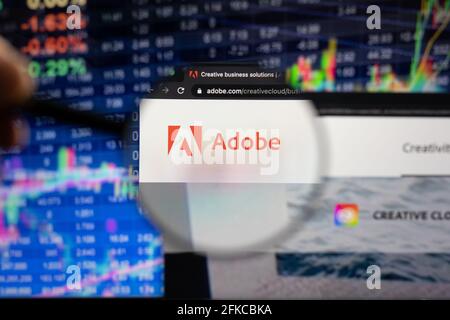 Adobe company logo on a website with blurry stock market developments in the background, seen on a computer screen through a magnifying glass Stock Photo