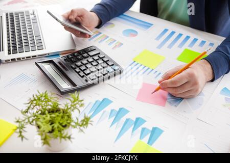 Businessman holding a pen is working with graph documents and sunset light background. Stock market chart and finger pointing on tablet in office. Stock Photo