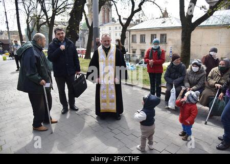 Lviv, Ukraine. 29th Apr, 2021. Priest greets people during the distribution of free food and Easter sets to the needy.On the eve of Orthodox Easter, which will be celebrated on May 2, the Emmaus Mutual Aid community in Lviv distributed Easter packages to homeless and low-income people. Credit: SOPA Images Limited/Alamy Live News Stock Photo