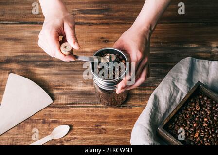 Closed view of grinding coffee in a metal and glass coffee grinder on a wooden table Stock Photo