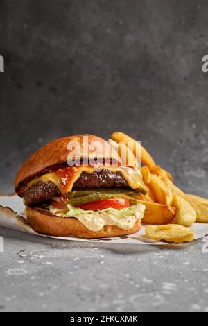 American cuisine. Royal Cheese Burger of Marble Beef with cucumbers, cheese and sauce. Healthy, tasty, nourishing snack. Take away food. Copy space Stock Photo