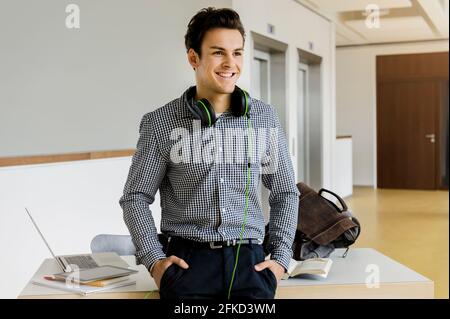 Germany, Bavaria, Munich, Smiling young man standing at desk Stock Photo