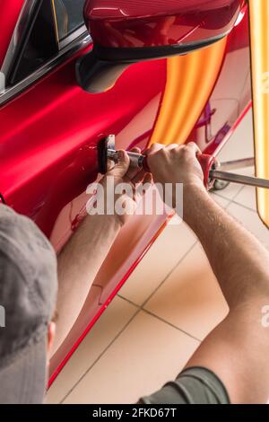 The technician removes dents on the car using the method without painting. PDR. Car body repair. Stock Photo