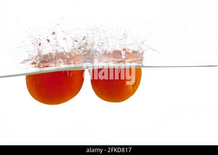 two tangerines falls into the water on a white background, isolate, place under the text Stock Photo