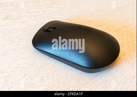 Black wireless computer mouse on wooden table side view Stock Photo