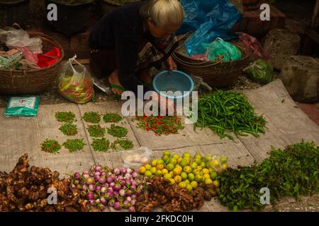 Luang Prabang, Laos - July 6, 2016:  A vendor separates peppers during an early morning market. Stock Photo