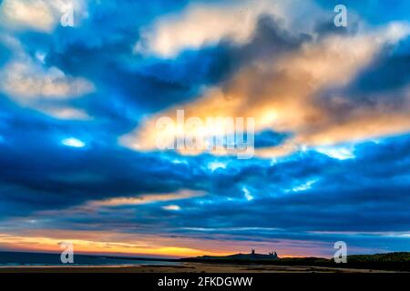 Sunrise over Dunstanburgh Castle, northumberland, in the North of England Stock Photo