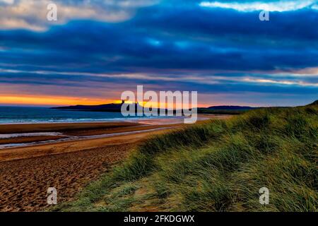 Sunrise over Dunstanburgh Castle, northumberland, in the North of England Stock Photo