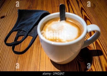 White coffee cup and chinstrap or mask on wooden table. Stock Photo
