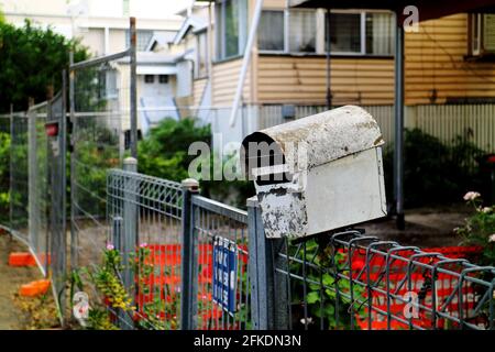 Old, rusty and beatup mailbox hanging on the edge of a fence Stock Photo