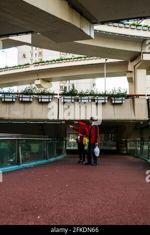 An old couple framed by the elevated roads crossing Yan’an East Road on a pedestrian bridge in central Shanghai, China. Stock Photo