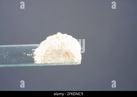 Closeup of white powder looking like drugs in front of a gray background Stock Photo