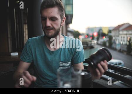 Handsome bearded Caucasian man holding a camera lens in a cafe Stock Photo