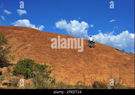 African worshippers going up a rocky hill to pray on clear day with blue sky in Limpopo, South Africa Stock Photo