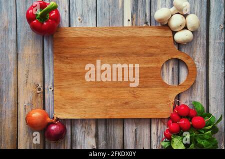 Wooden cutting board on wooden background with vegetables Stock Photo
