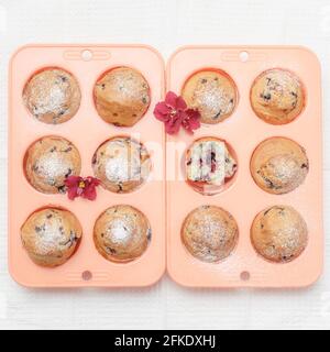 Fresh baked muffins or cupcakes in pink silicone baking tins, top view Stock Photo