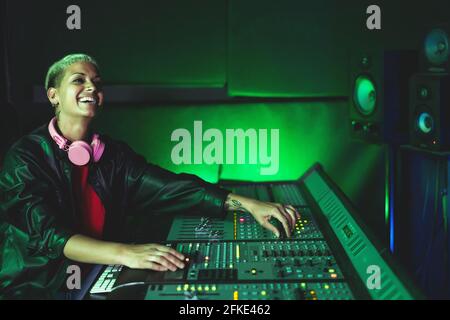 Young woman working in music recording studio - Female audio engineer mixing a sound in production house Stock Photo