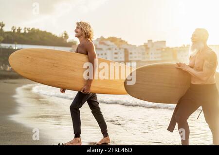 Happy friends with different age surfing together - Sporty people having fun during vacation surf day - Extreme sport lifestyle concept Stock Photo