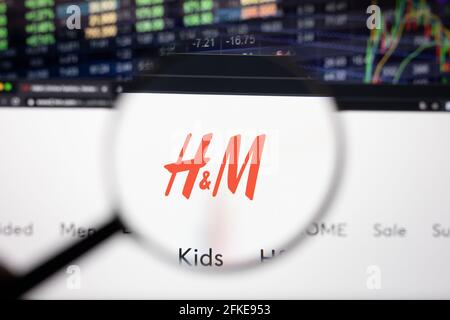 H and M company logo on a website with blurry stock market developments in the background, seen on a computer screen through a magnifying glass Stock Photo