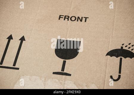 Word Front and three symbols on cardboard box - This Way Up, Keep Dry and Fragile for careful transportation. Close-up. Stock Photo